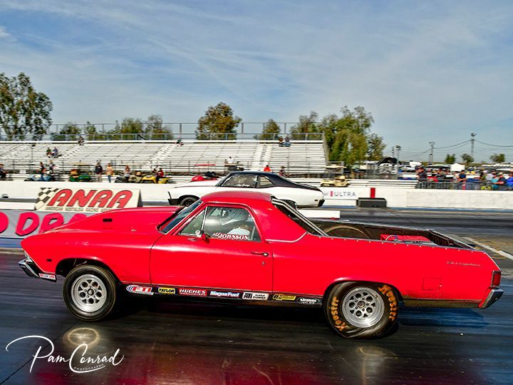 A red pickup truck is parked on the side of a race track.