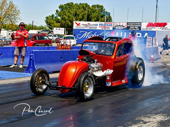 A red car is doing a burnout on a race track.