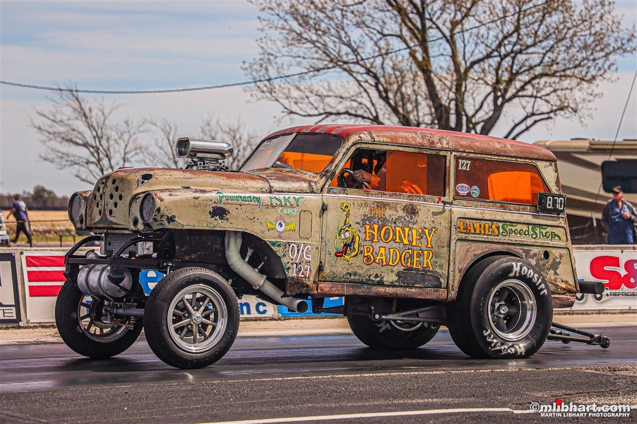 A rusty old car is parked on the side of the road.