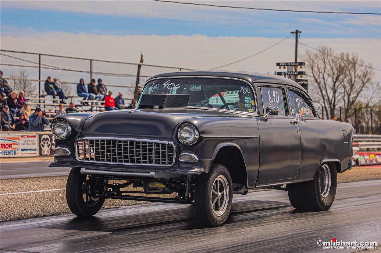 A black car is driving down a race track.