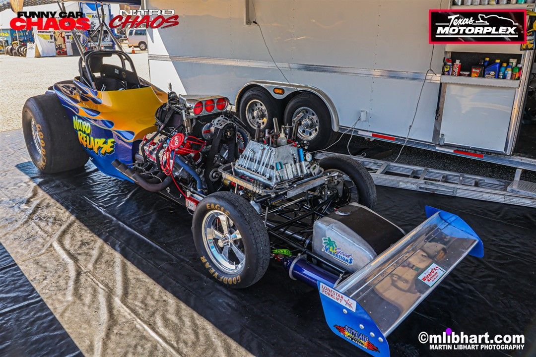 A racing car is parked on the ground next to a trailer.