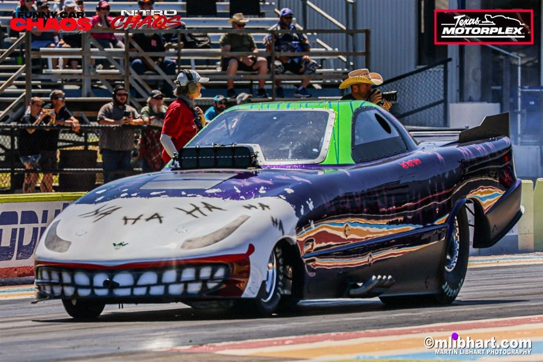 A joker racing car is driving down a race track.