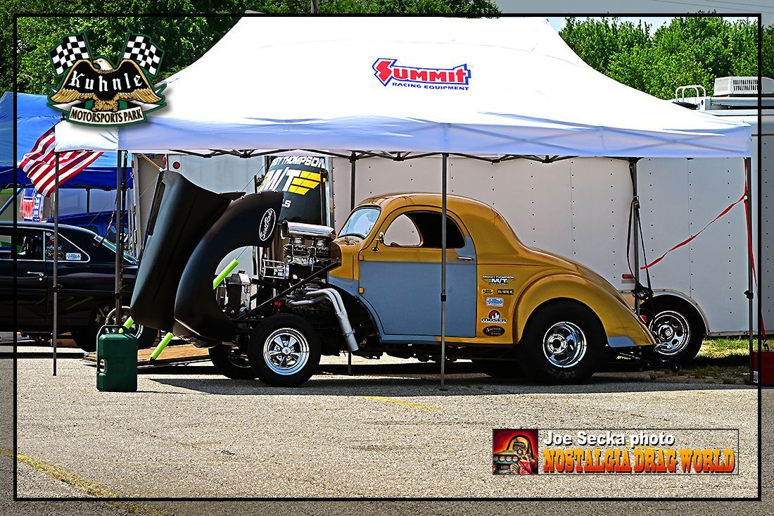 A yellow car is parked under a white tent with the number 8 on it