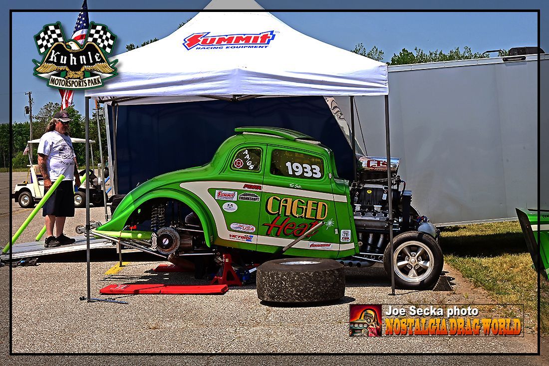 A green cheetah car is parked under a white tent