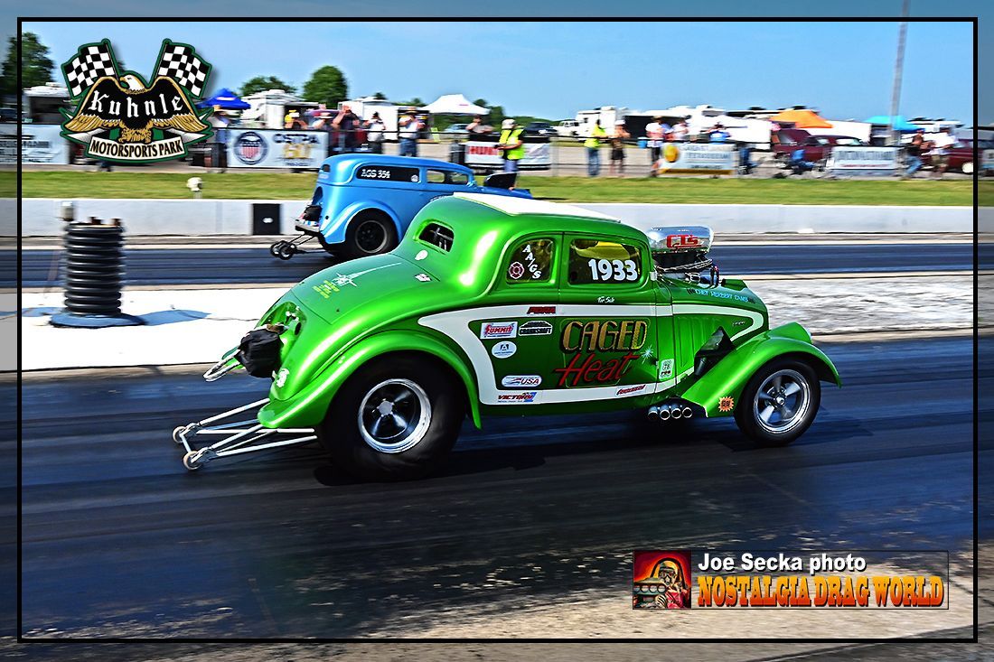 A green car is driving down a race track.