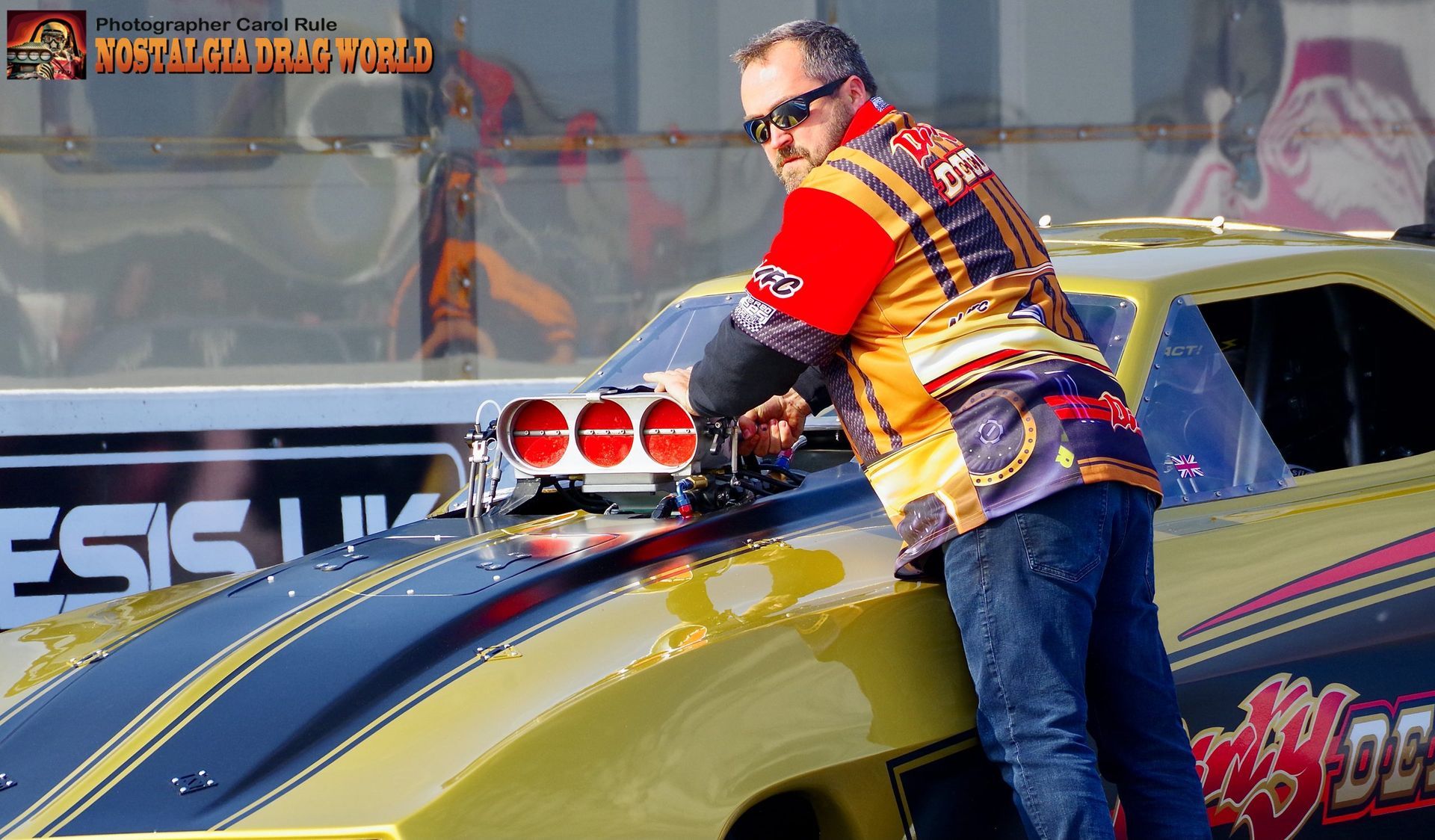 A man is standing next to a race car that says esc on the side