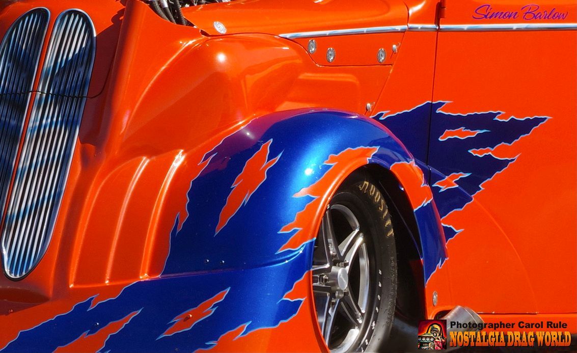 A close up of an orange car with blue flames painted on it