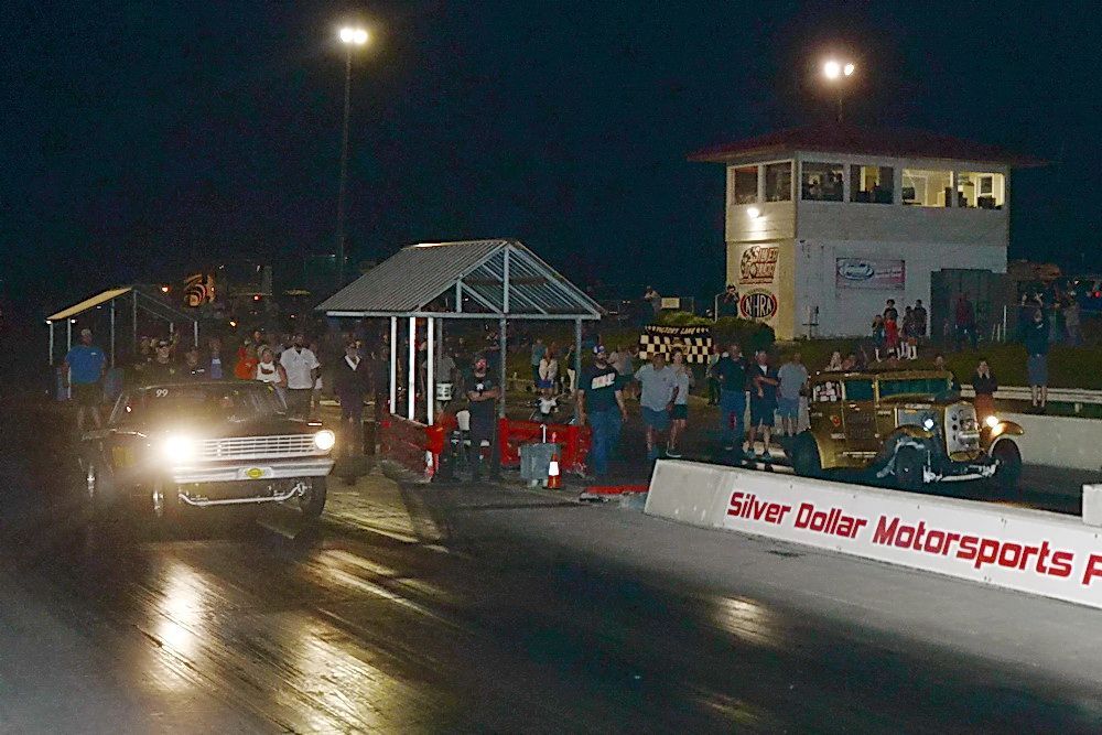 A car is driving down a race track at night.