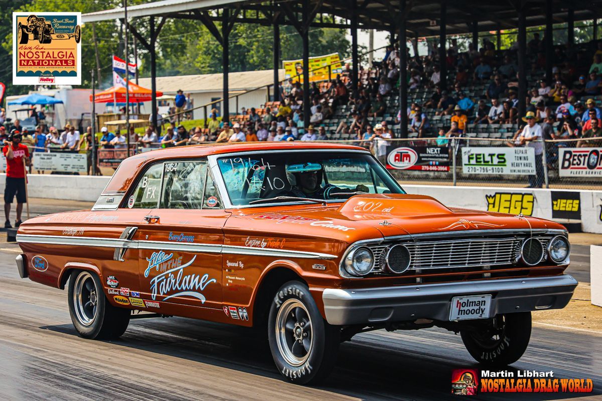 A classic car is driving down a race track.