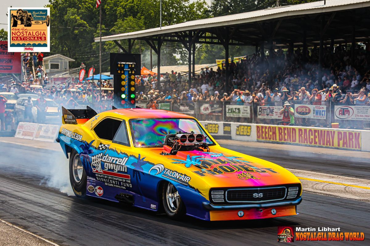 A colorful muscle car is driving down a race track.