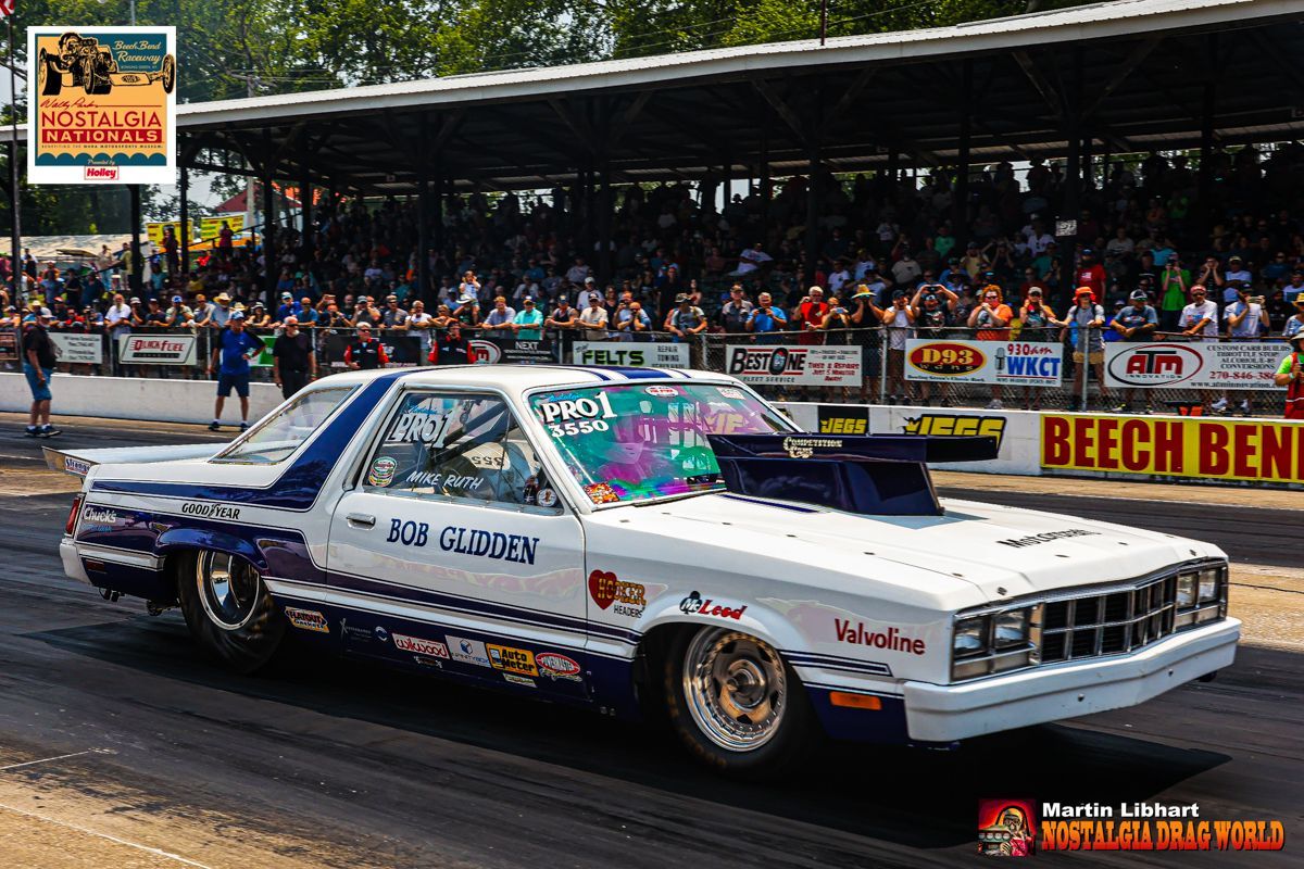 A white and blue race car is driving down a track.