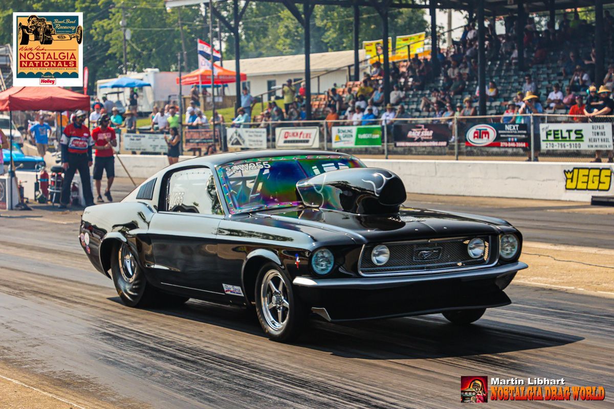 A black mustang is driving down a race track.