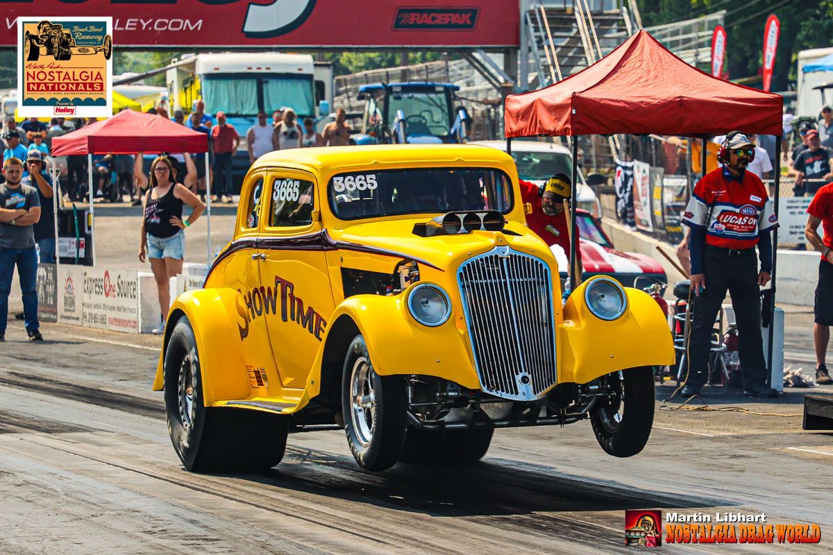 A yellow car is driving down a race track.