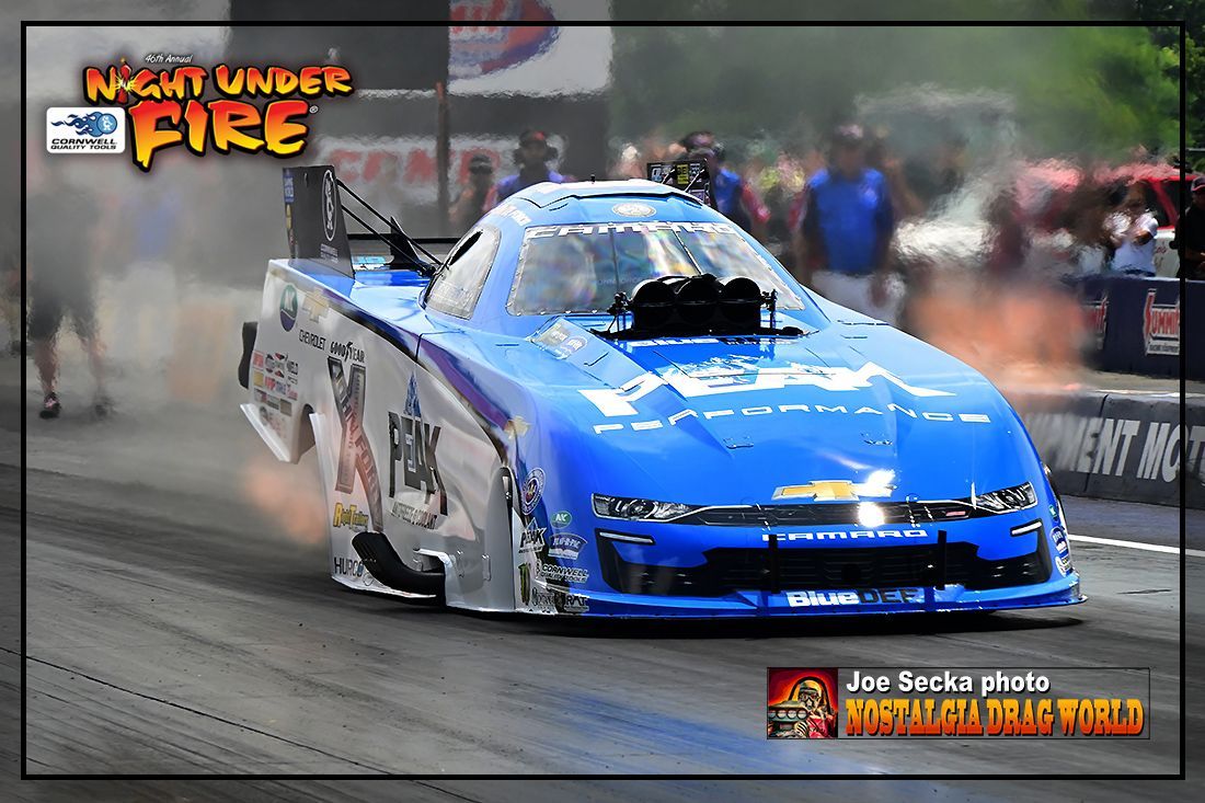 A blue race car is on a track with the words night under fire above it