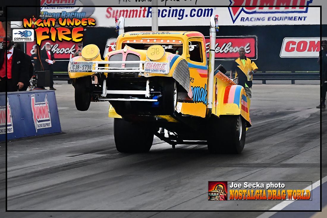 A colorful truck is on a race track with a sign that says night under fire