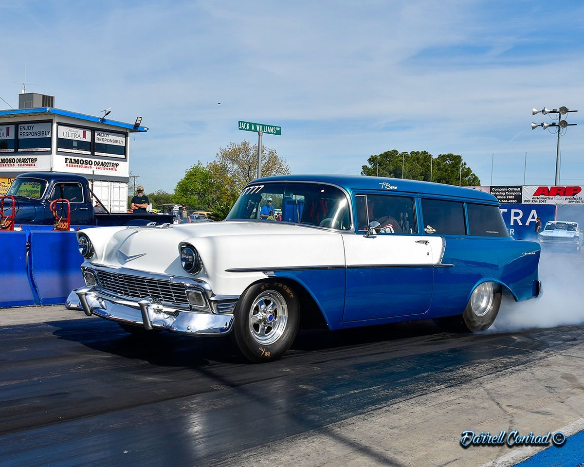 A blue and white car is driving down a race track