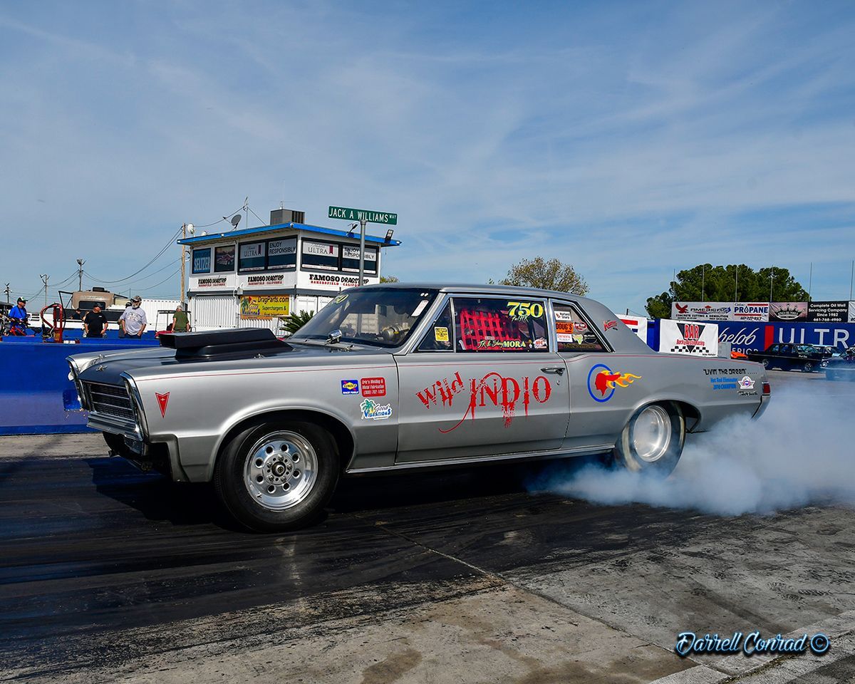 A silver car is doing a burnout on a race track.