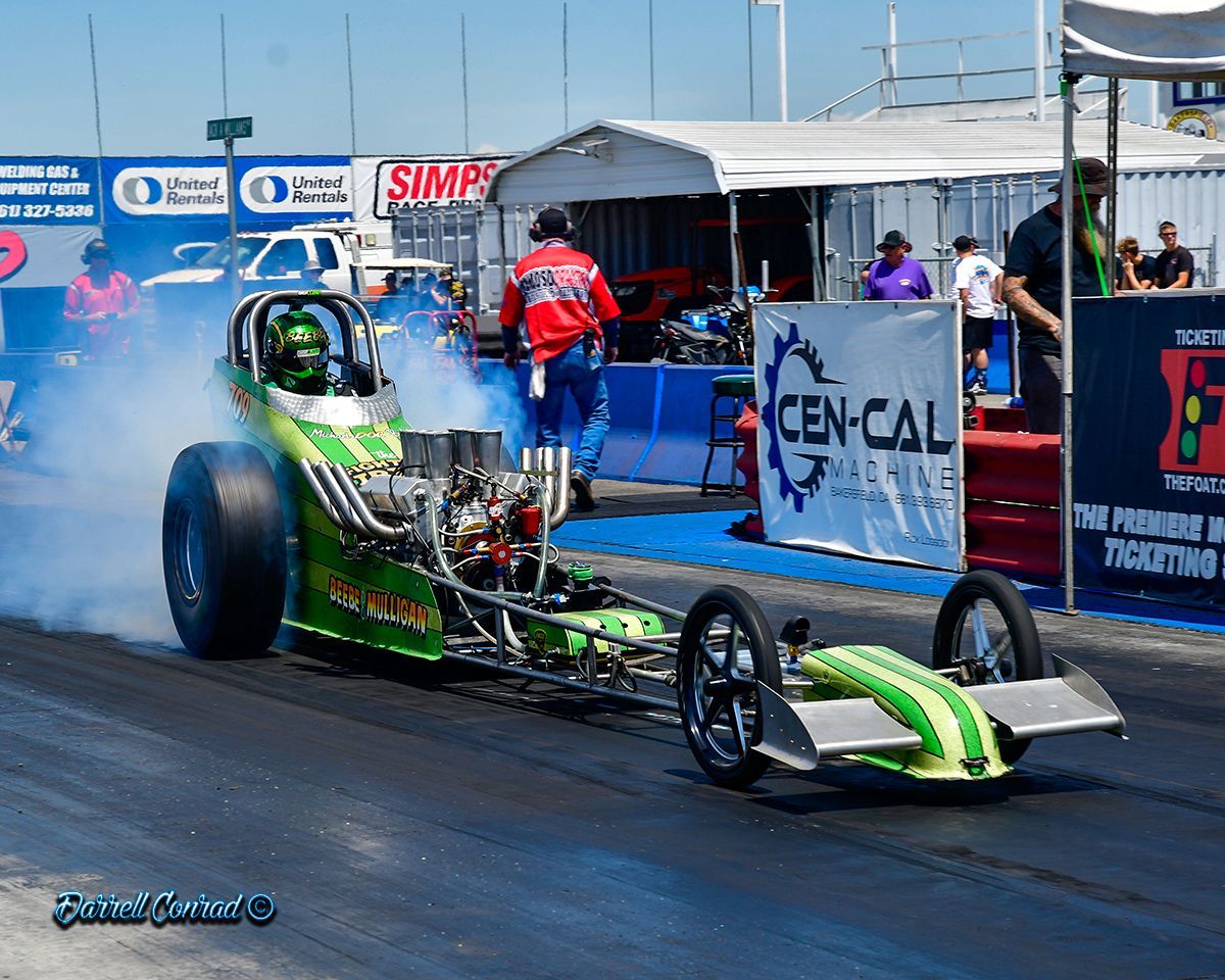 A green and yellow drag race car is on a race track