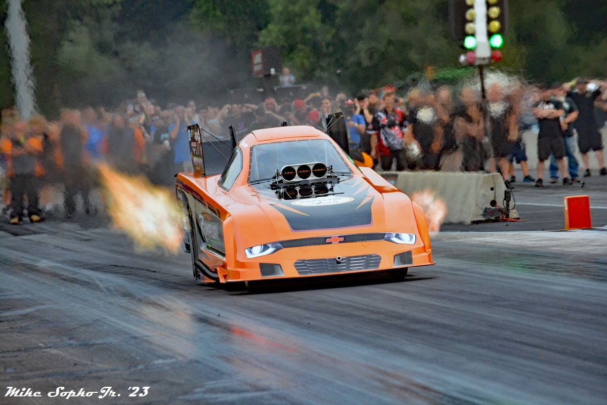 A race car is doing a burnout in front of a crowd.