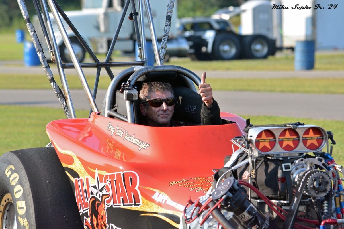 A man is sitting in a red race car with the word star on it