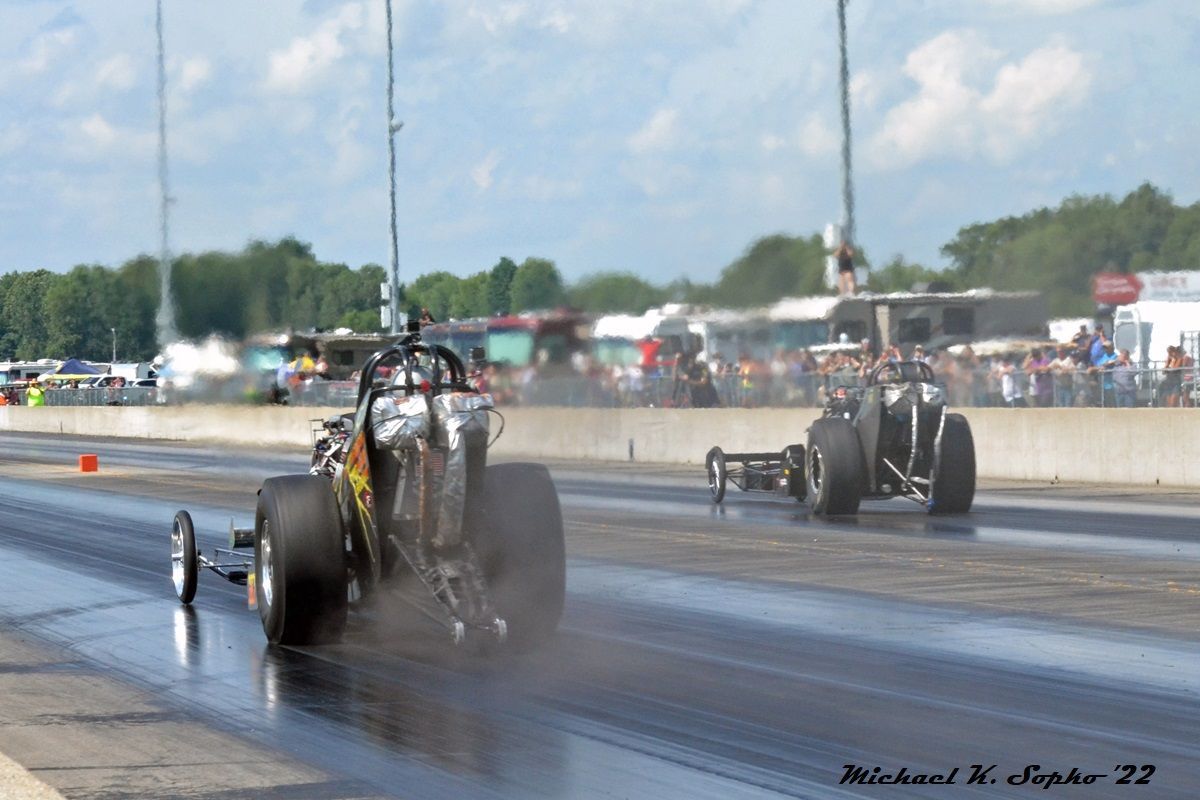 Two drag racing cars are racing on a wet track