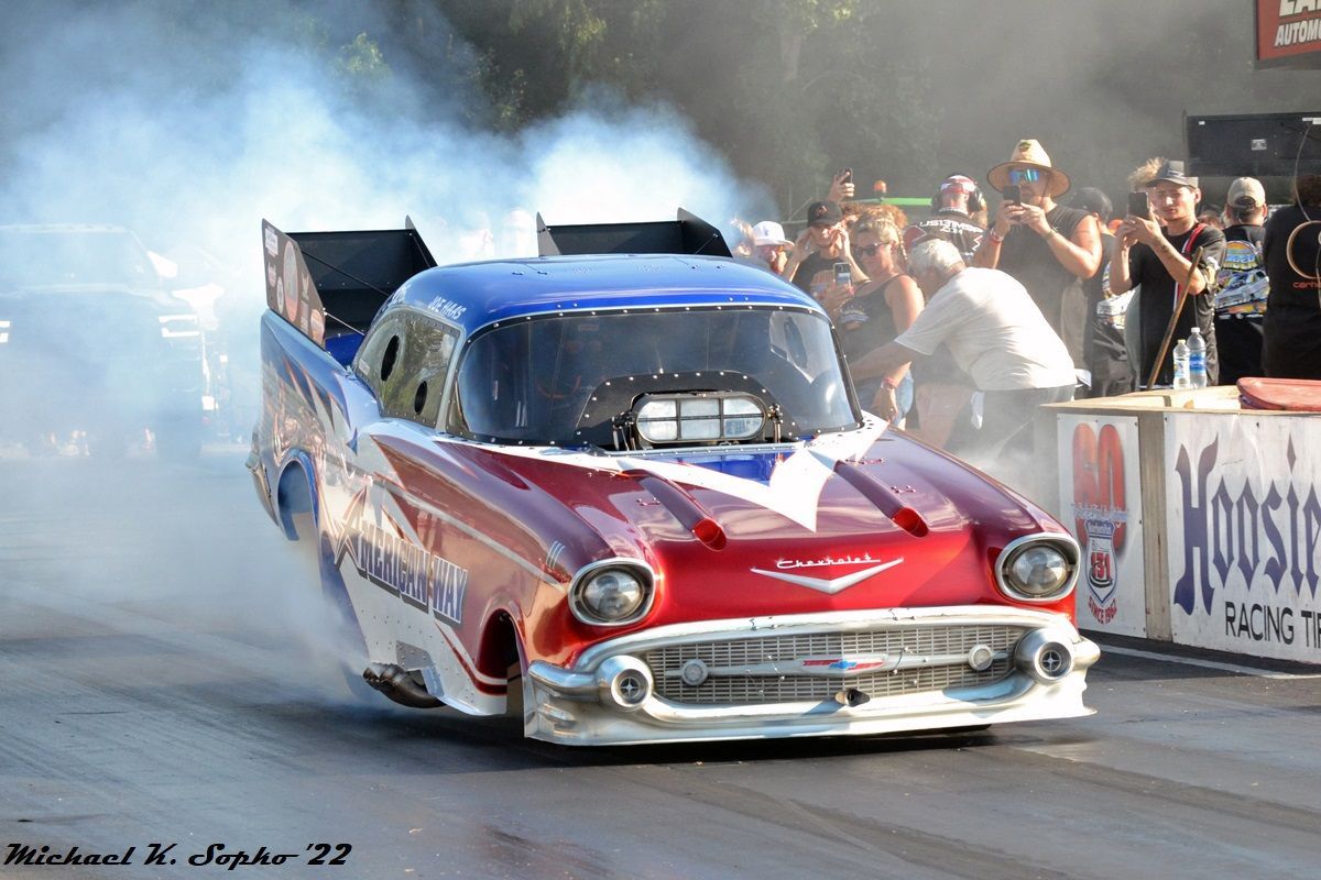 A red white and blue car is driving down a race track.