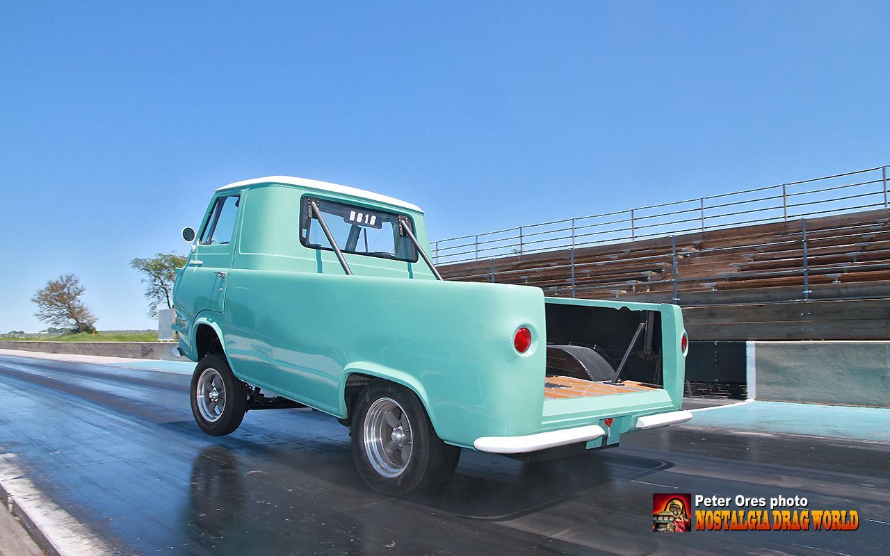 A green truck is parked on the side of the road.