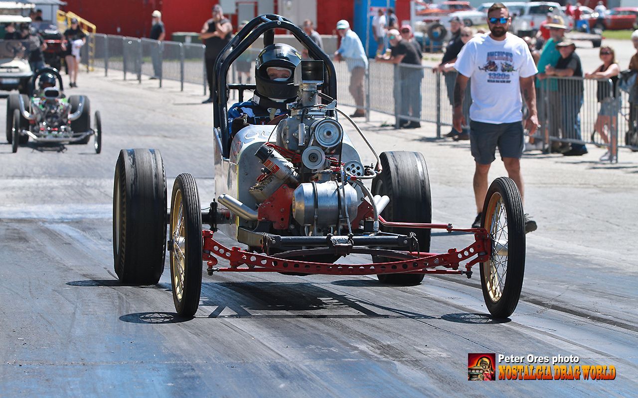 A man in a white shirt is standing next to a racing car
