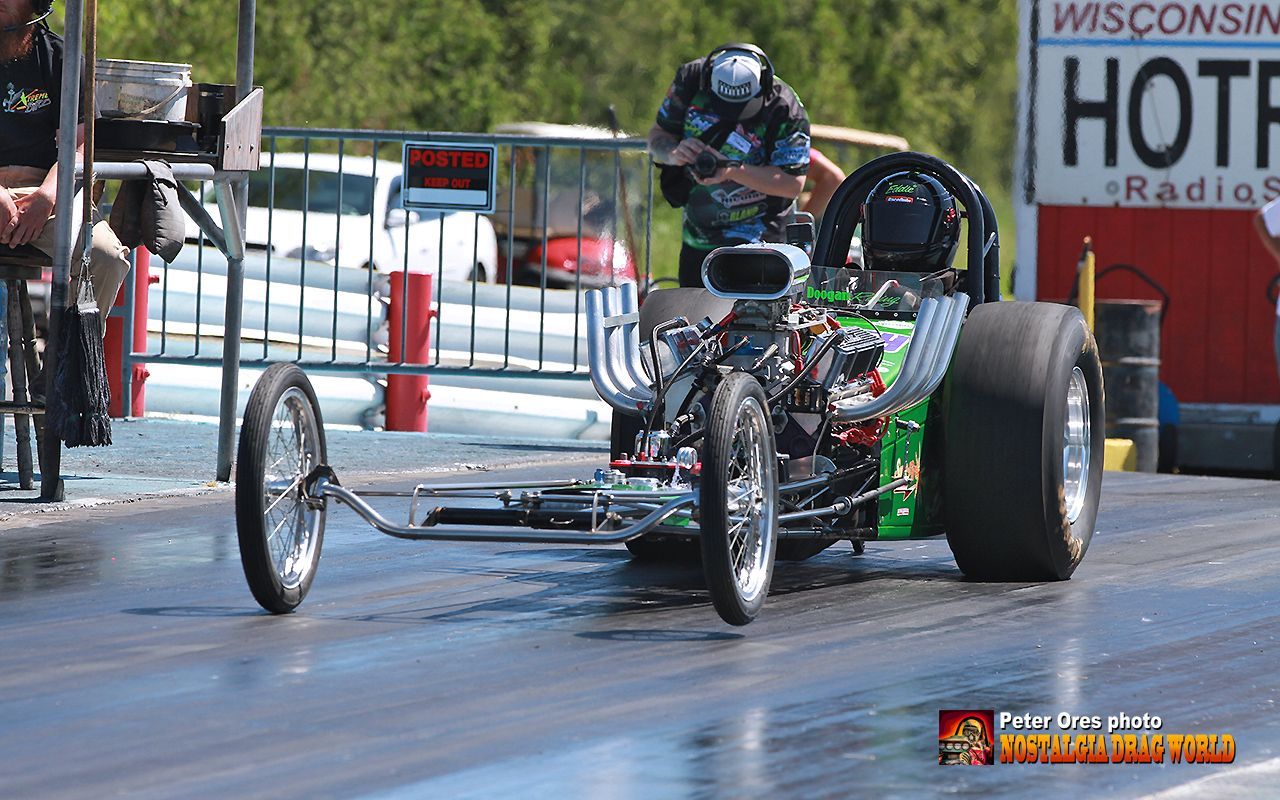 A man is standing next to a motorcycle on a race track.