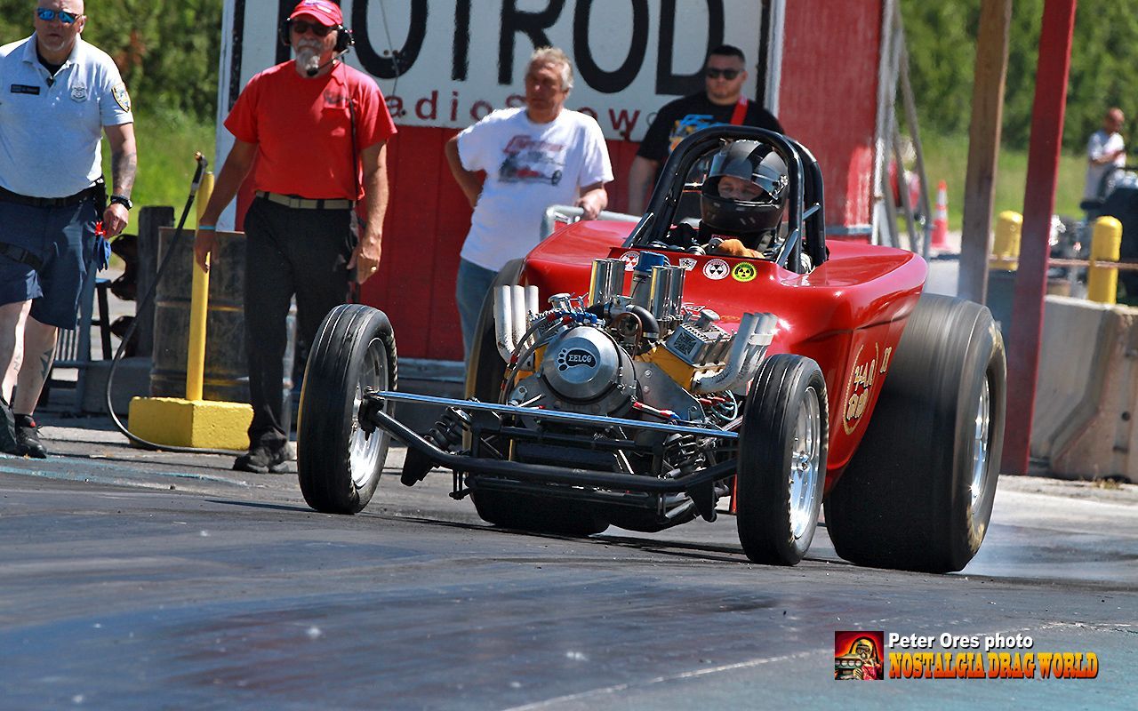 A man is driving a red buggy on a race track