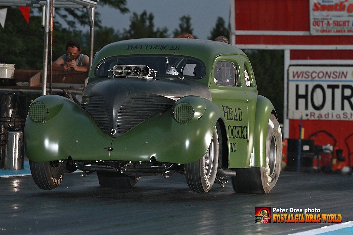 A green car is driving down a race track in front of a sign that says hotr