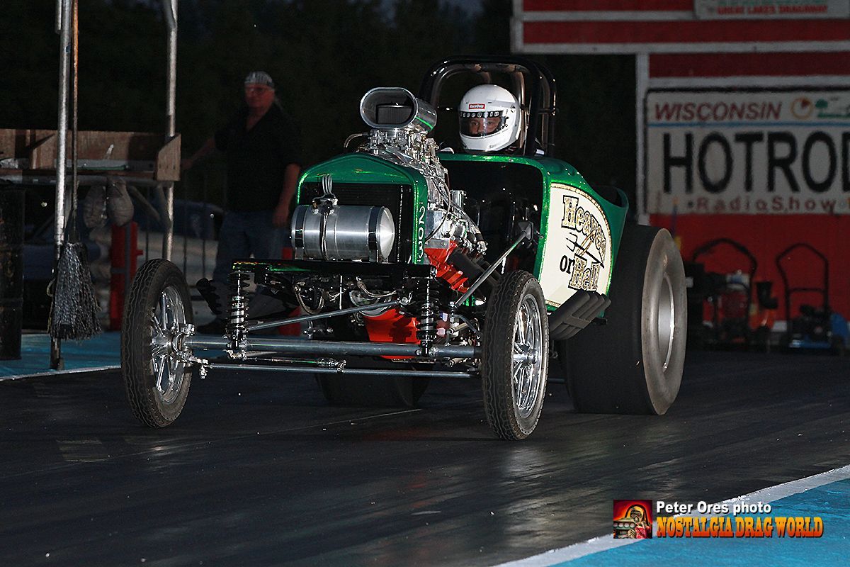 A green race car is on a track with a wisconsin hot rod sign in the background
