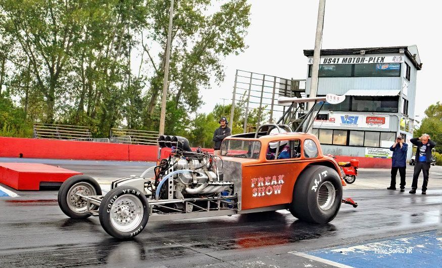 A drag car is being driven on a race track.