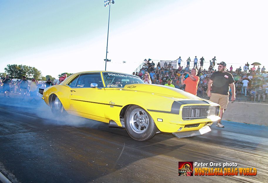 A yellow car is doing a burnout on a race track.