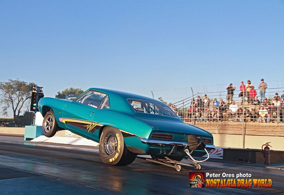 A blue car is doing a trick on a race track.