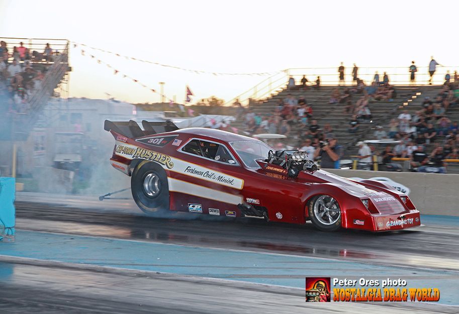 A red and white race car is doing a burnout on a track.