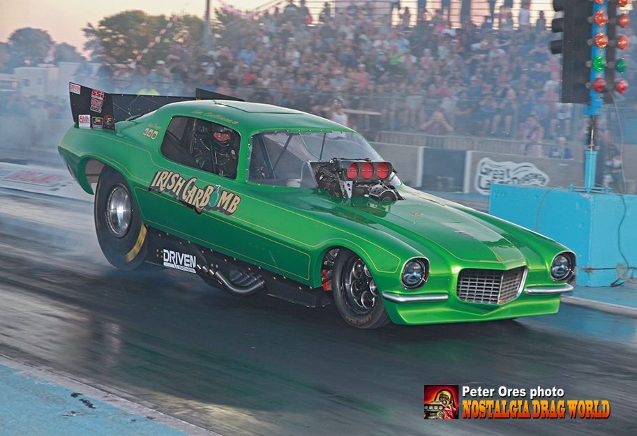 A green racing car is driving down a race track.