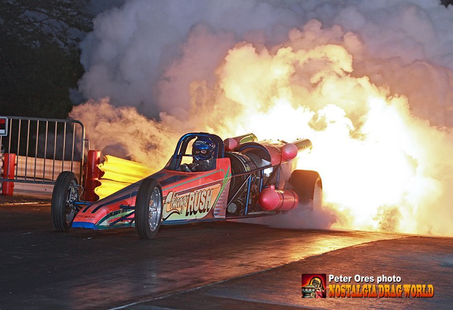A drag racing car with flames coming out of it 's tires