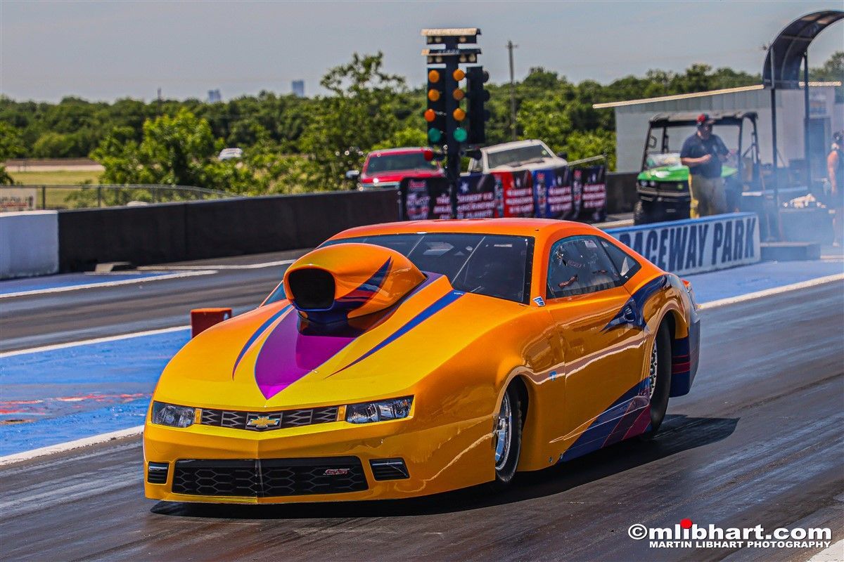 A yellow and purple race car is driving down a race track.