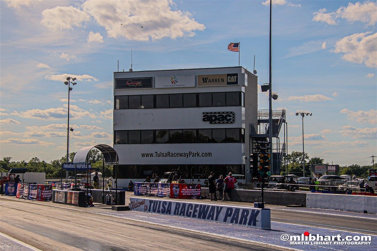 A race car is parked in front of a building that says raceway park.