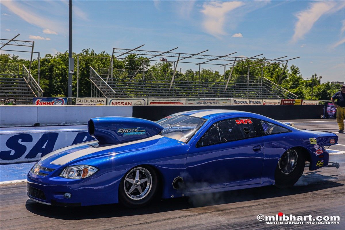 A blue car is driving down a race track.