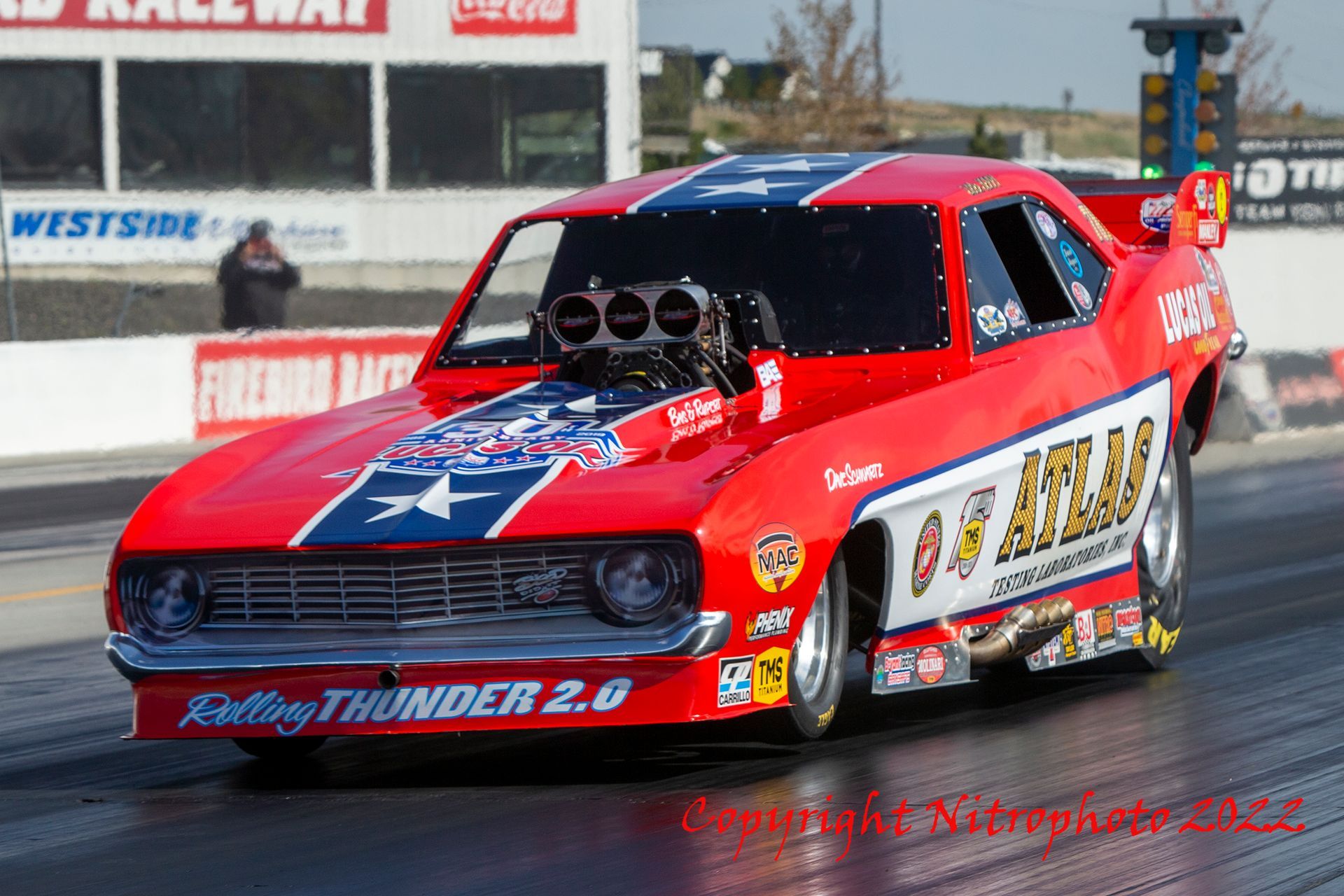 A red racing car is driving down a race track.