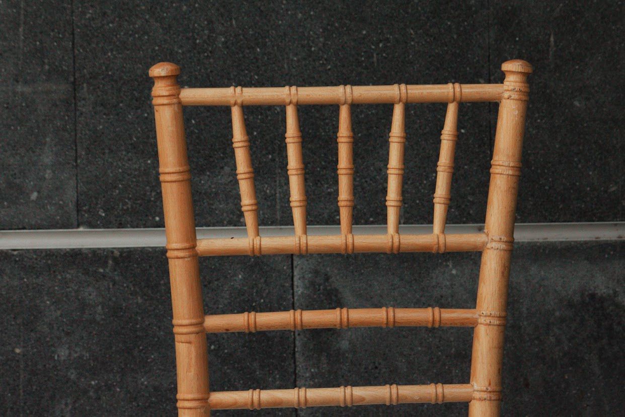 Respaldo de silla de madera con husillos verticales sobre una superficie texturizada oscura.