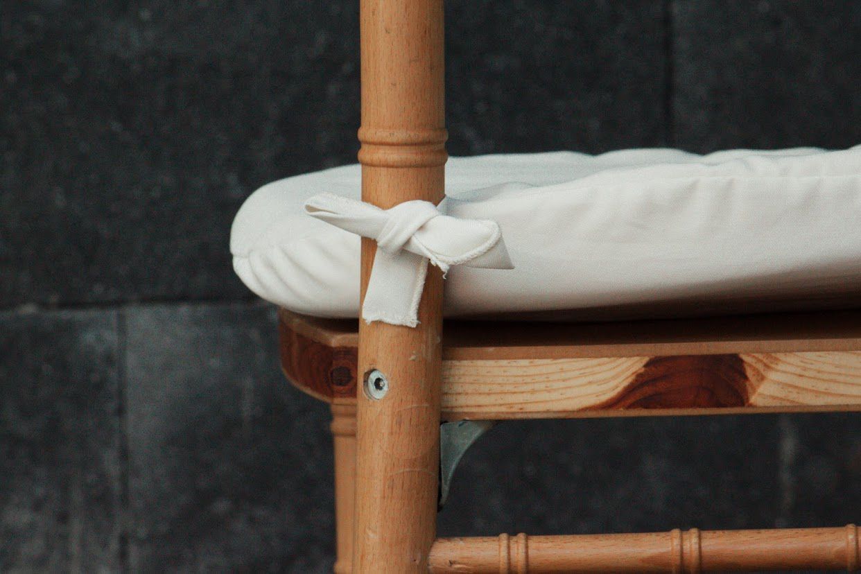 Silla de madera con cojín blanco atado al marco.