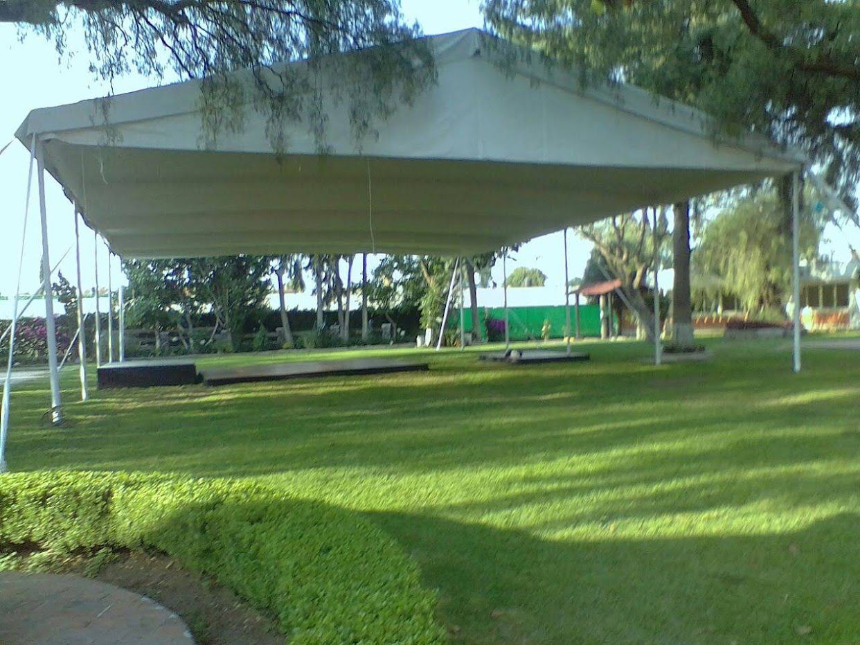 Gran carpa blanca sobre césped verde; árboles al fondo.
