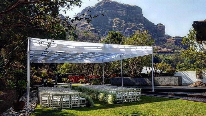 Montaje de boda con sillas, dosel y fondo de montaña.