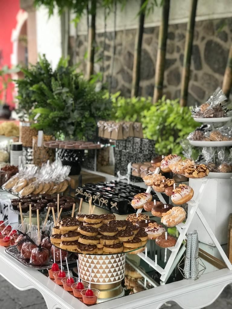 Mesa de postres con dulces variados: manzanas cubiertas de chocolate, galletas, donas y brownies.