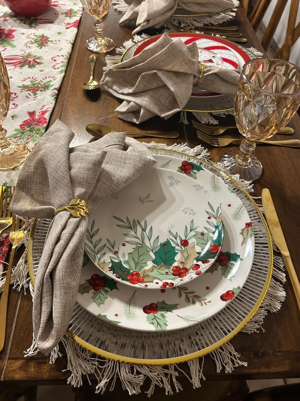 Mesa navideña con platos florales, cubiertos dorados y servilletas color canela.
