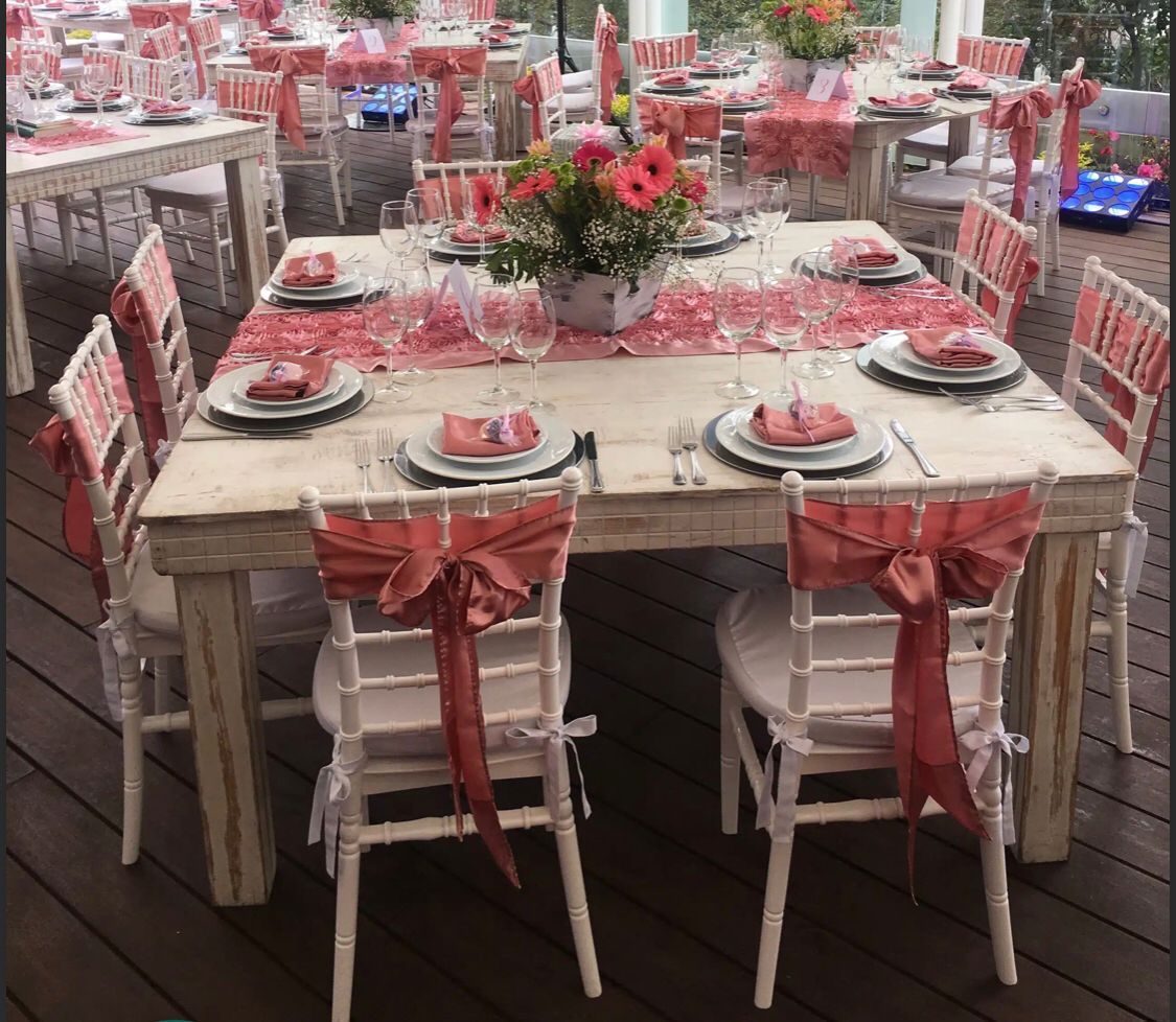 Mesas de recepción de boda preparadas con lazos de coral y centros de mesa florales.