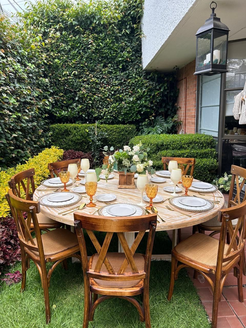 Mesa de comedor al aire libre para invitados, rodeada de vegetación.
